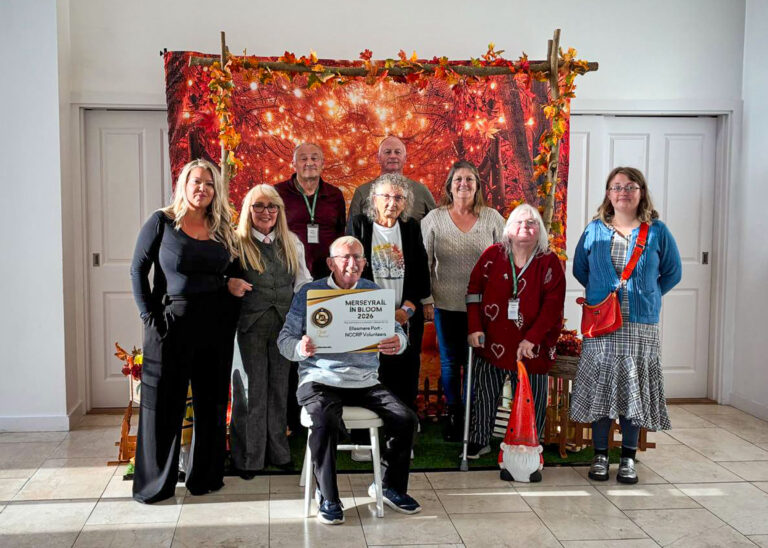 Friends of Ellesmere Port Station celebrate their Gold Award at the Merseyrail in Bloom Awards 2026, holding their award plaque.