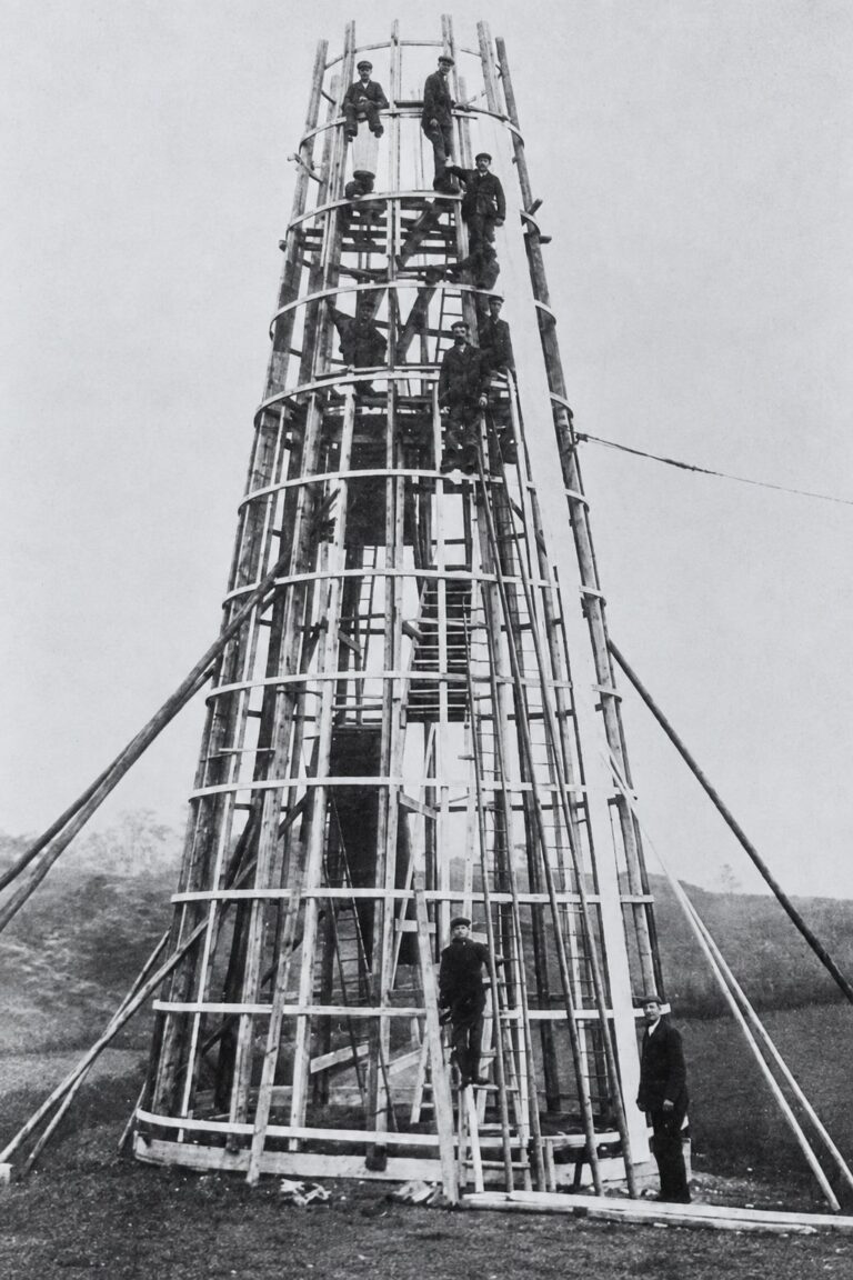Workmen constructing the Mersey View helter-skelter in Frodsham in 1908, with several men positioned along the wooden structure.